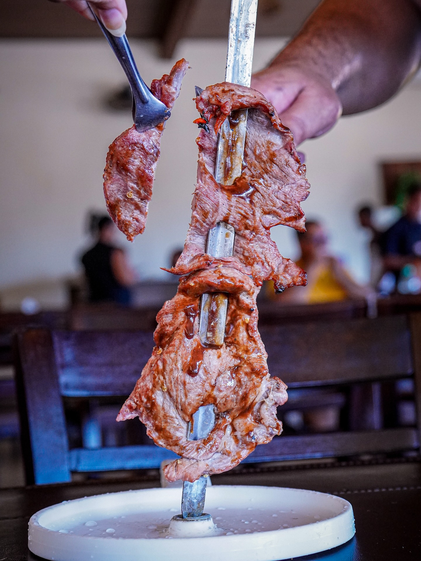 Carne no espeto sendo fatiada no rodízio